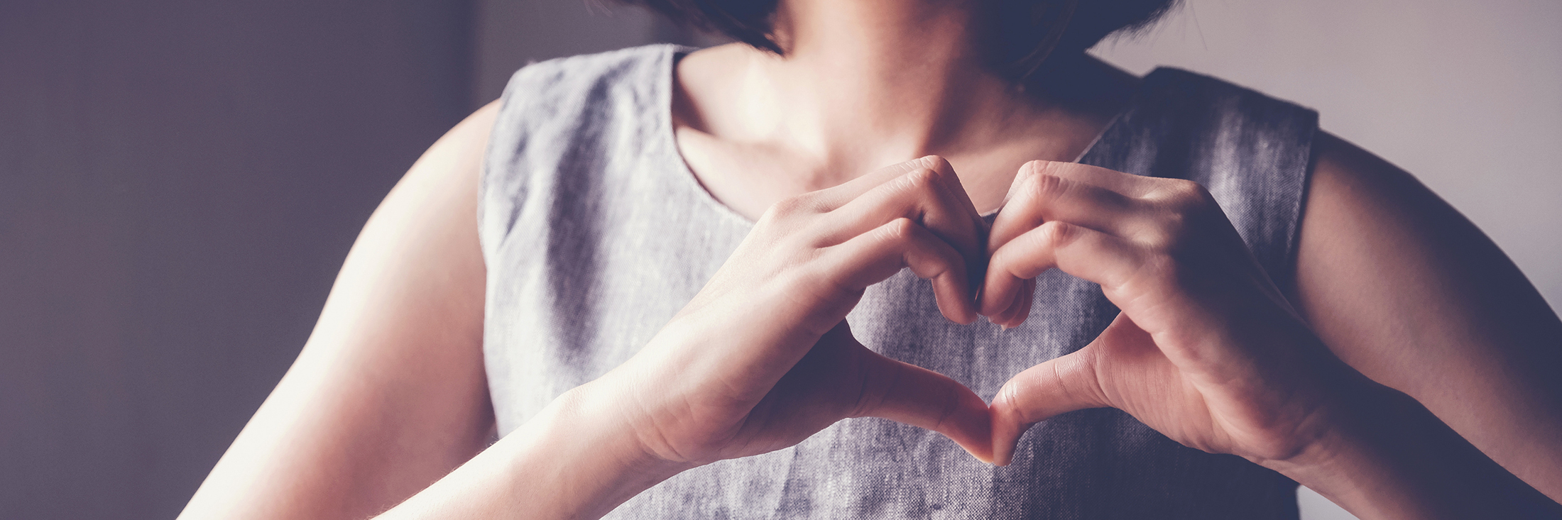 Woman with hands formed as a heart in front of her chest