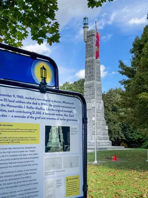 Large information sign, in front of a tower, surrounded by trees
