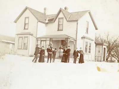 Very old photo of people standing in front of a house