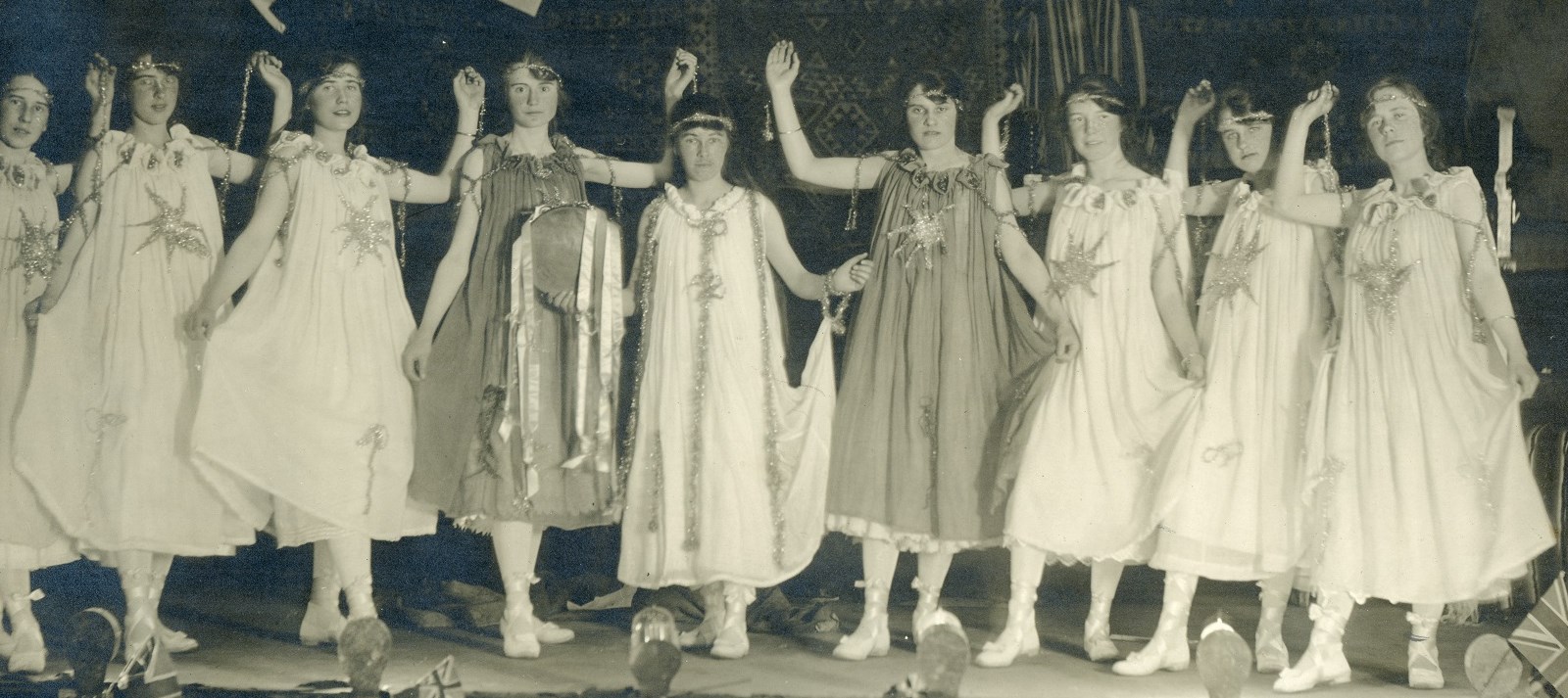 "Black and white photo of nine women standing on stage in various poses, 1918"