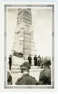 Black and white picture, with people in suits and military uniforms, standing in front of a tower war memorial