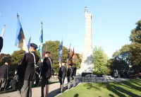 People in uniform at attention, beside a tower