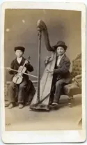 Black and white picture with two people seated, one playing violin and the other, harp